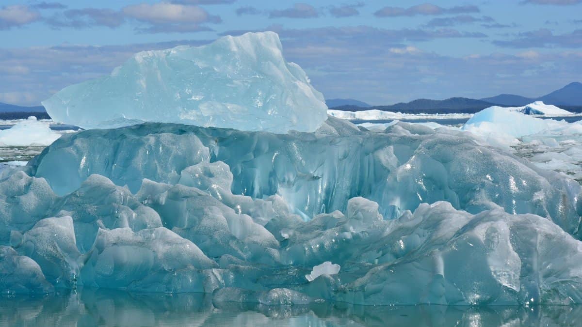 Stunning iceberg captured in clear Arctic waters, highlighting melting ice and climate change impact.