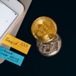 Bitcoin coins and smartphone displaying price chart with investment notes.