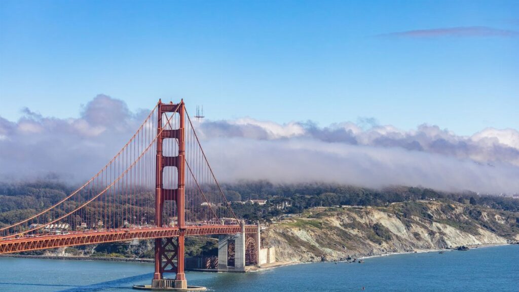 A stunning aerial view of the iconic Golden Gate Bridge with clouds and a blue sky in San Francisco.