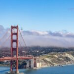 A stunning aerial view of the iconic Golden Gate Bridge with clouds and a blue sky in San Francisco.
