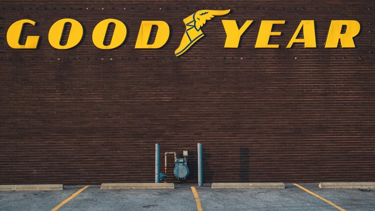 A brick wall featuring a Goodyear sign above an empty parking lot.