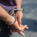 Close-up of an individual's hands in handcuffs, symbolizing arrest or crime.