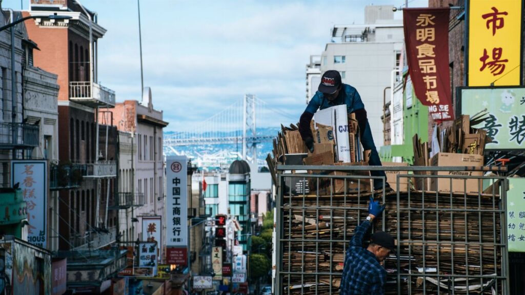 Urban scene in Chinatown with workers loading cardboard, city street view.