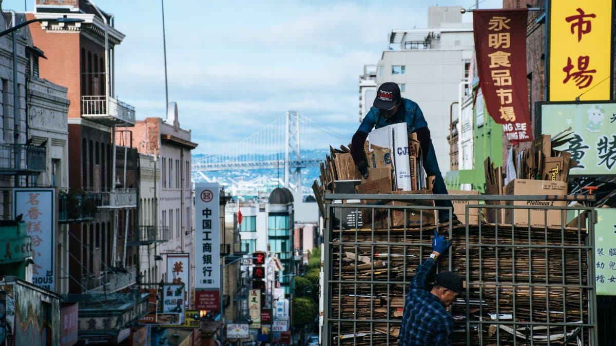 Urban scene in Chinatown with workers loading cardboard, city street view.