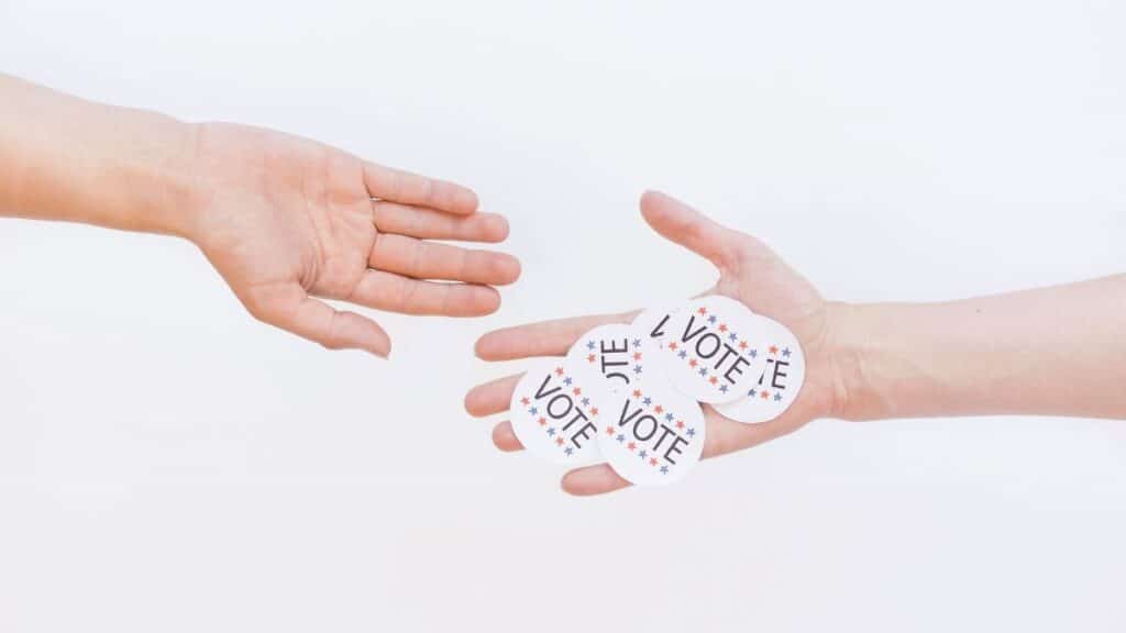 Close-up of hands exchanging vote stickers, symbolizing engagement in democratic election.
