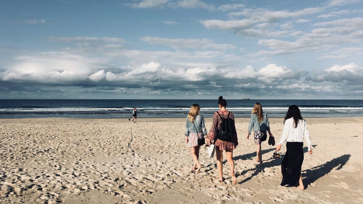 Four women walking on a sunny beach in Skinners Shoot, NSW, Australia. Ideal for vacation and travel themes.
