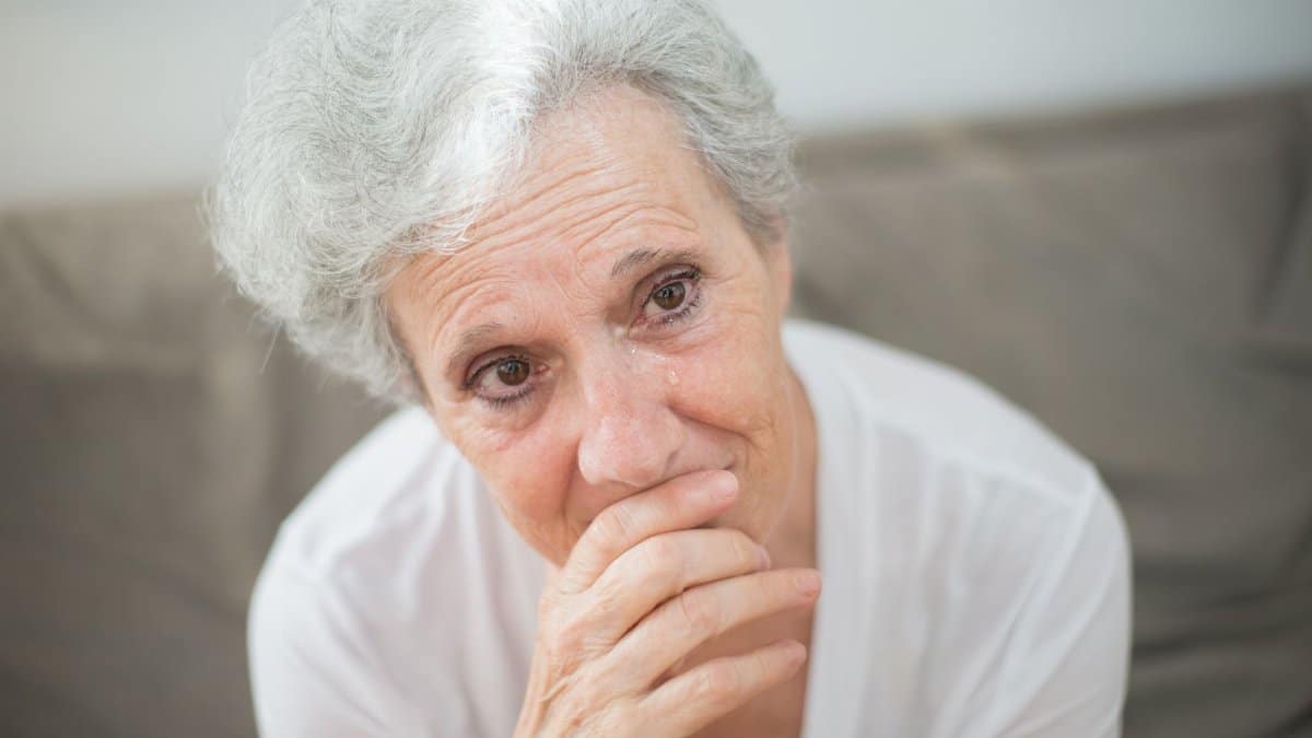 A thoughtful elderly woman with tears in her eyes, conveying deep emotions.
