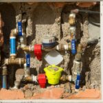 Detailed view of a complex water meter setup embedded in a concrete wall.