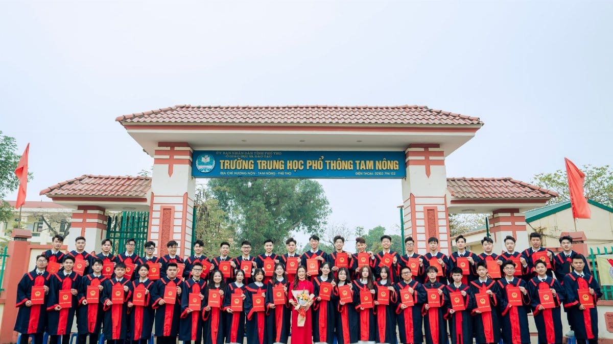 Group of students in graduation attire outside Tam Nong High School. Celebrating academic achievement.