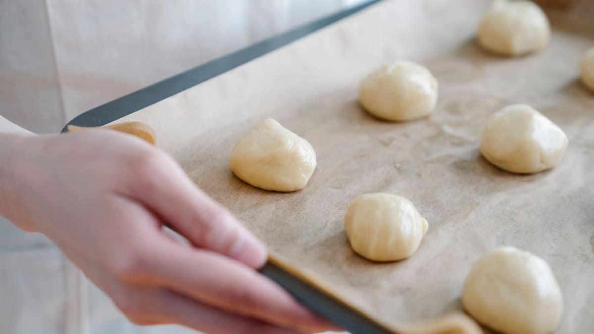 Close-up of homemade dough balls on parchment-lined baking tray, ready for oven.
