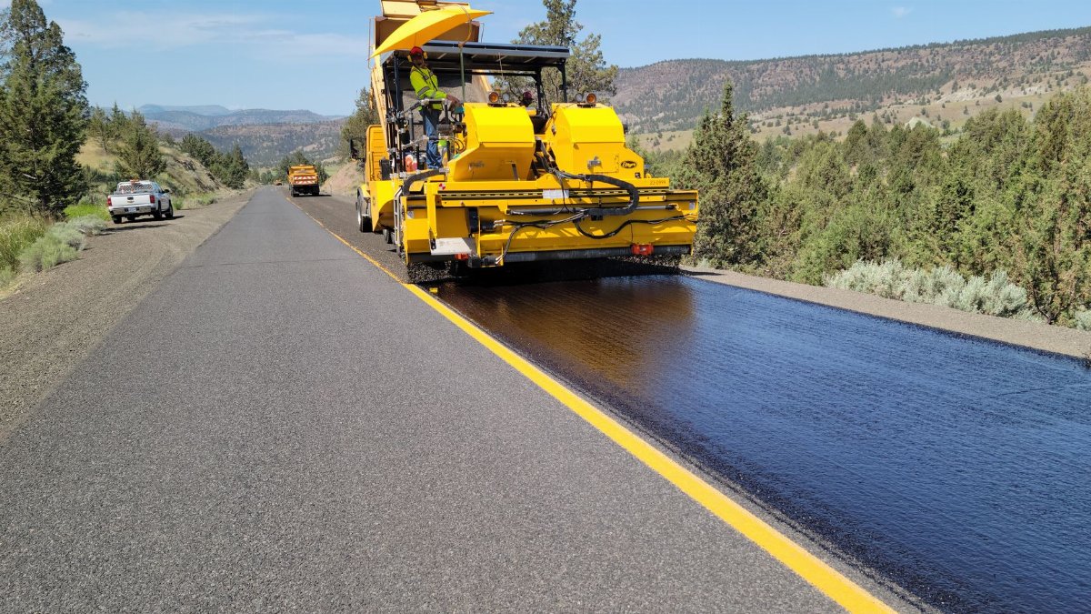 Road construction with paving machine in rural Oregon, highlighting infrastructure development.