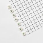 Alphabet letters spelling 'Teacher' on a white grid paper, highlighting education theme.