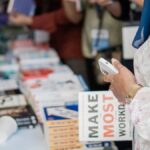 Close-up of various books on display at a book fair with attendees browsing.
