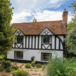 Explore a picturesque Tudor style cottage nestled in the rural village of Latimer, England, surrounded by lush greenery.