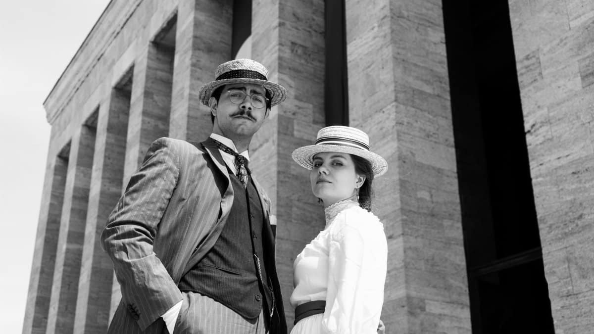 Stylish couple in vintage attire posing at Anıtkabir, Ankara.