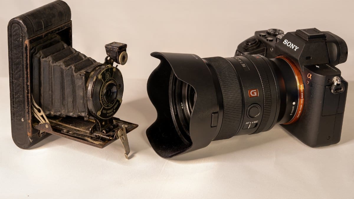 A vintage bellows camera next to a modern DSLR showcasing the evolution of photography technology.