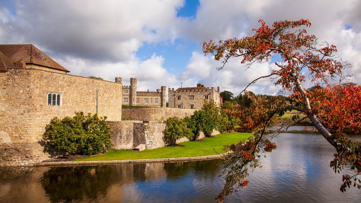 Stunning view of Leeds Castle surrounded by a moat and vibrant autumn leaves in Broomfield, UK.