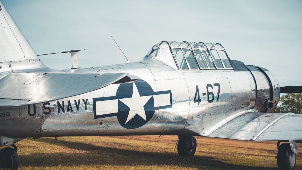 A vintage U.S. Navy aircraft stationed on a grassy field, displaying historical aviation design.