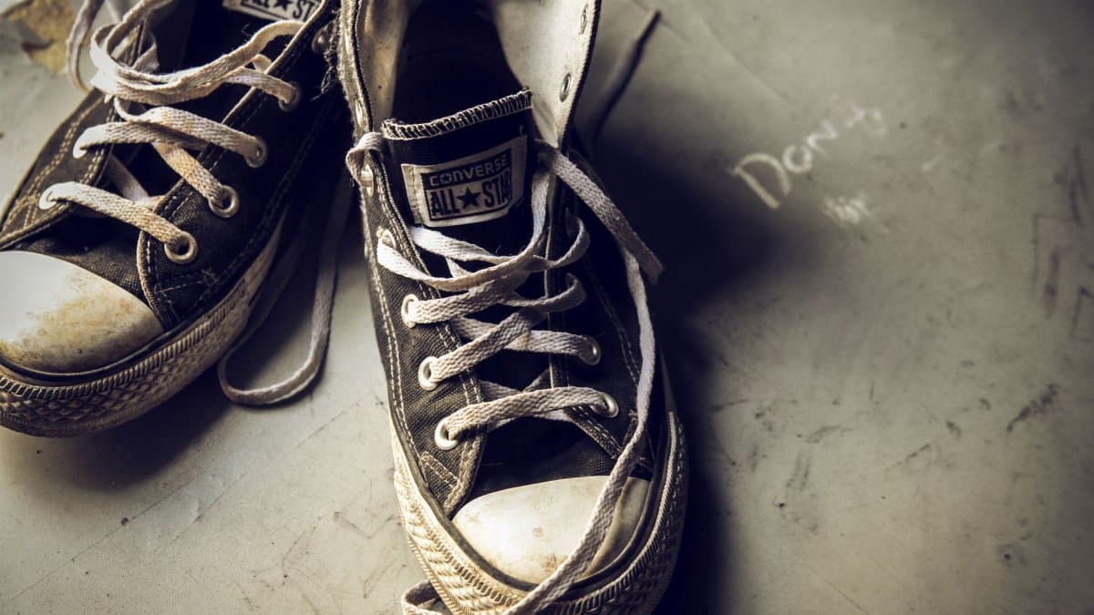 Close-up of worn Converse All Star sneakers, capturing a vintage and retro vibe on a muted background.