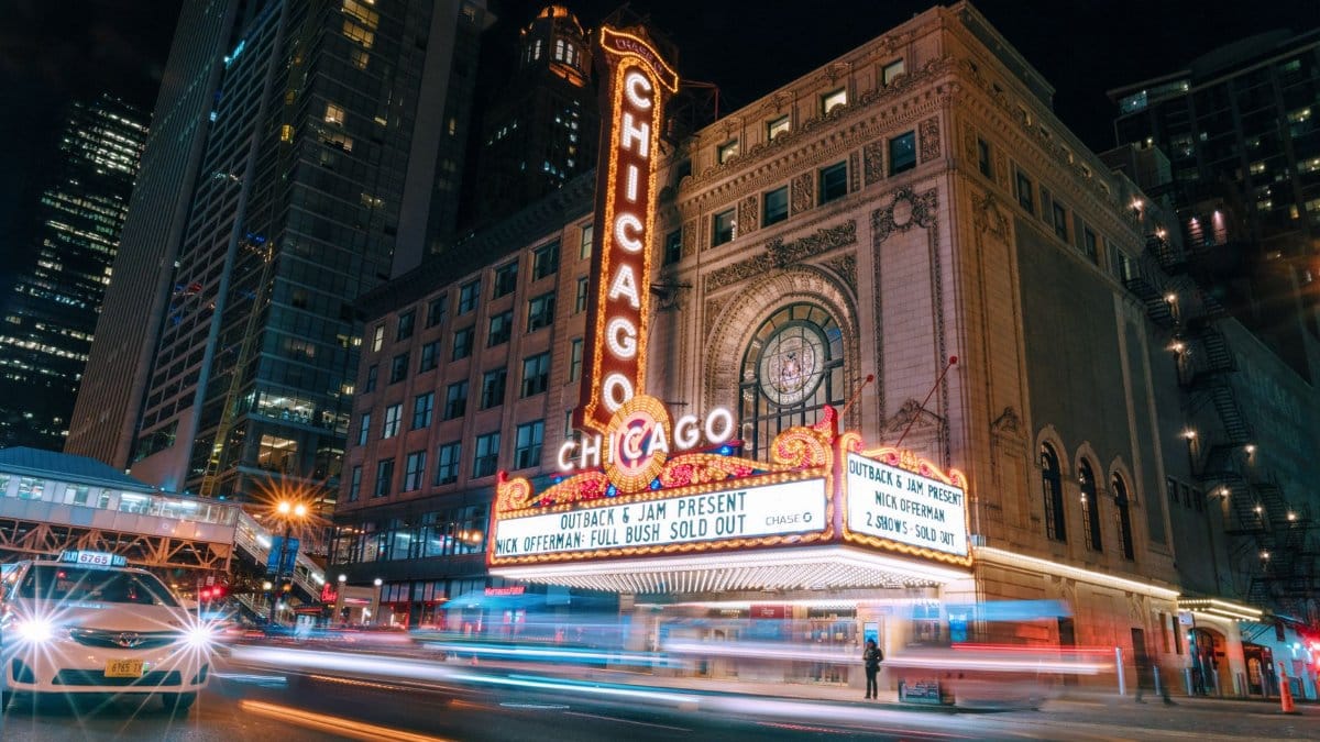Illuminated Chicago Theater sign with vibrant city nightlife.