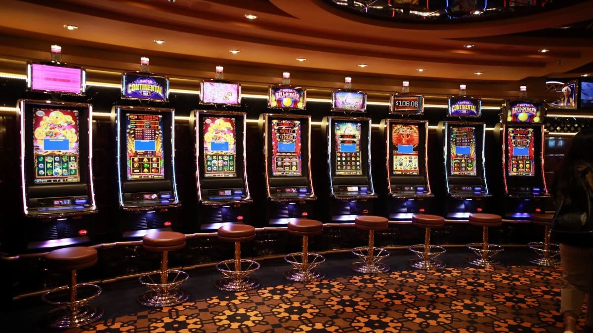 A row of luxury slot machines in a casino interior with plush stools, perfect for gaming enthusiasts.