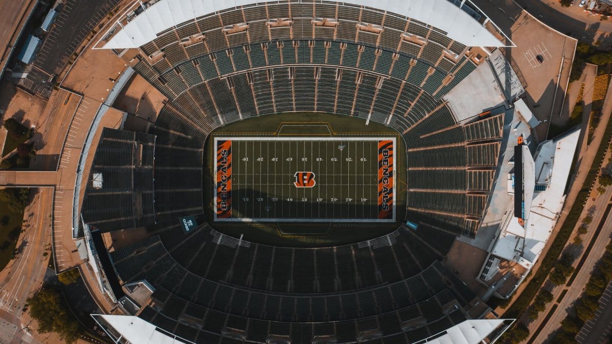 From above drone view of empty American football stadium with white lines and emblem on sunny day