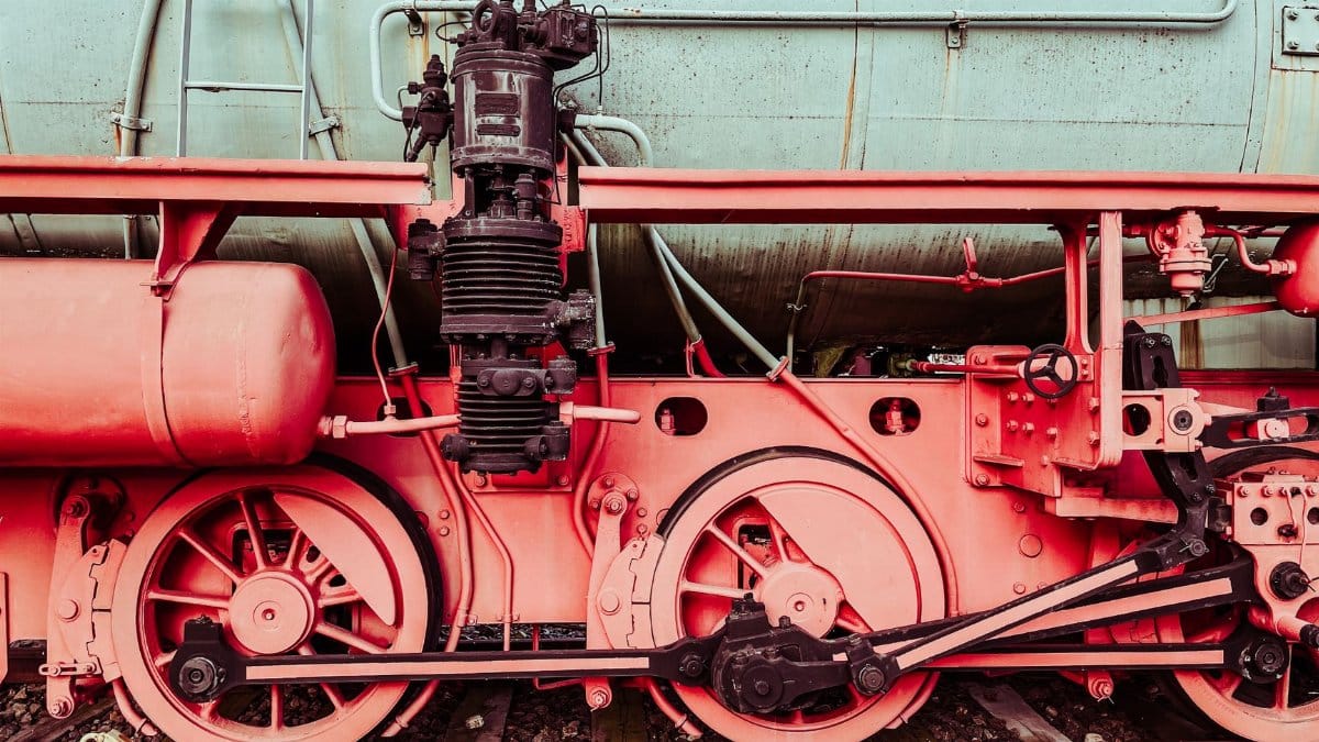 Detailed close-up of a vintage steam locomotive's wheels and mechanical parts. Industrial and historical charm.