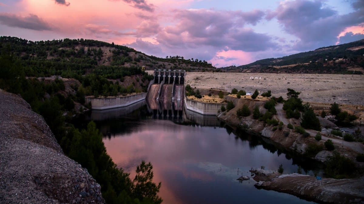 A breathtaking view of a dam and reservoir reflecting a colorful sunset sky.