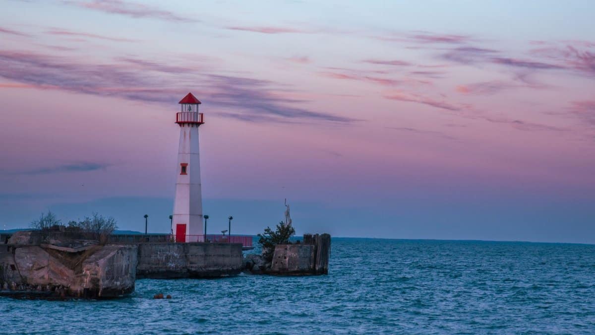 Beautiful view of a lighthouse on Mackinac Island, Michigan at sunset with calm waters and pastel sky.
