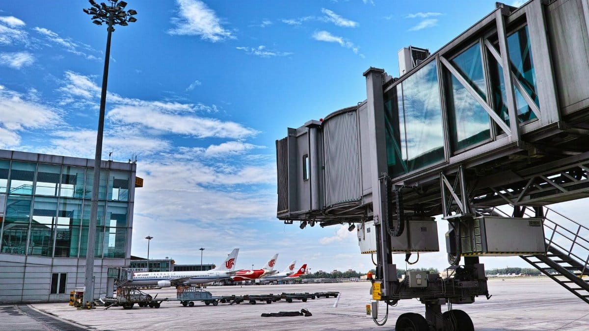 A jet bridge connects an aircraft at a busy airport on a clear day.