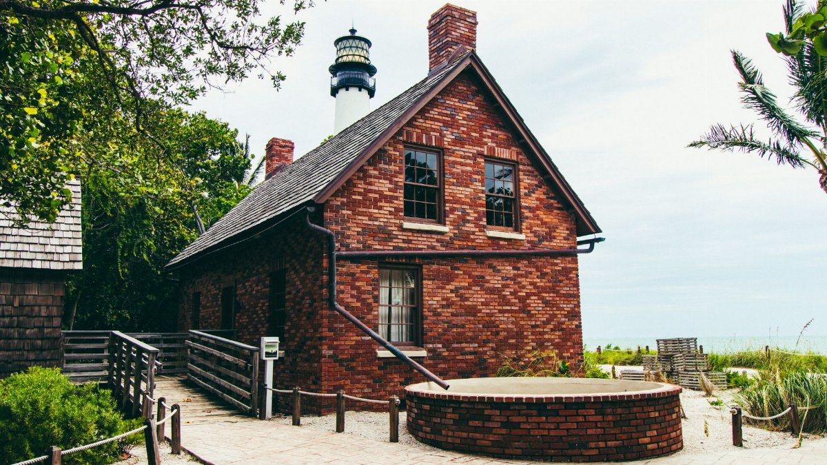 A charming brick house near the Cape Florida Lighthouse, Key Biscayne, surrounded by lush greenery.