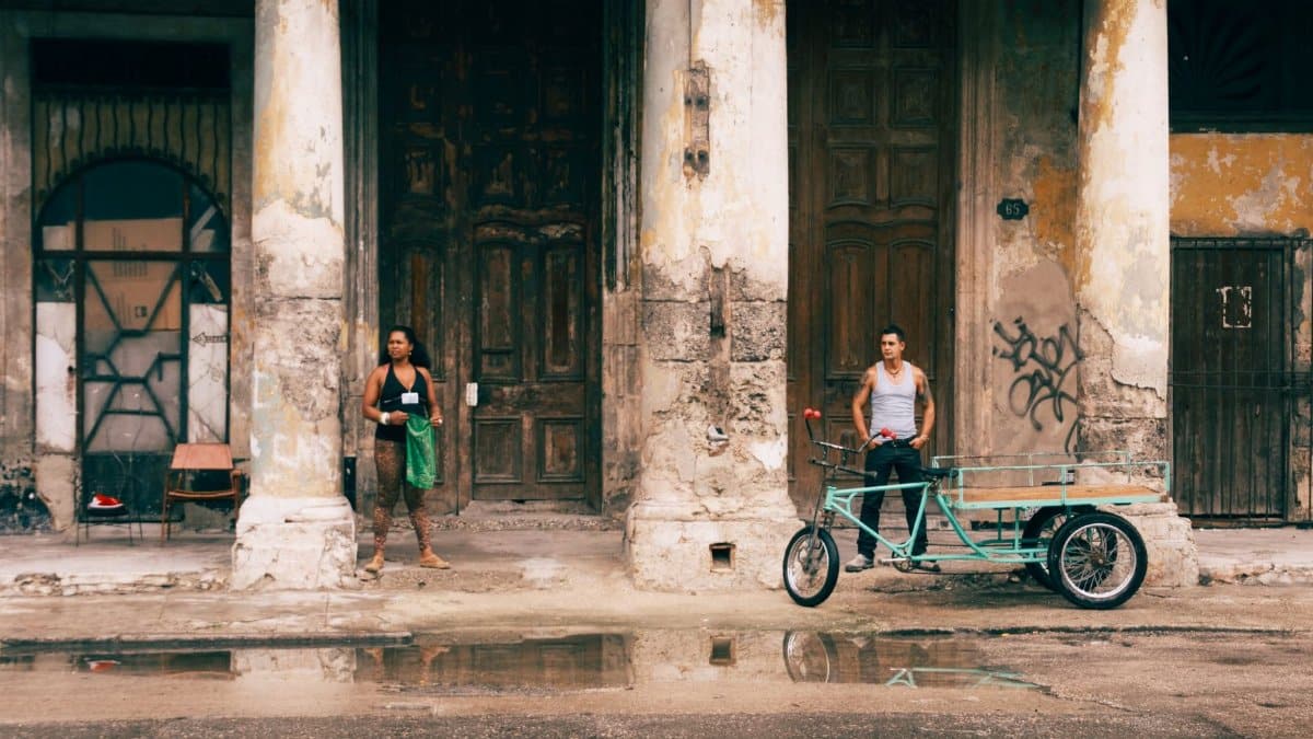 Man and woman in front of historic building in Havana, Cuba with bicycle cart.