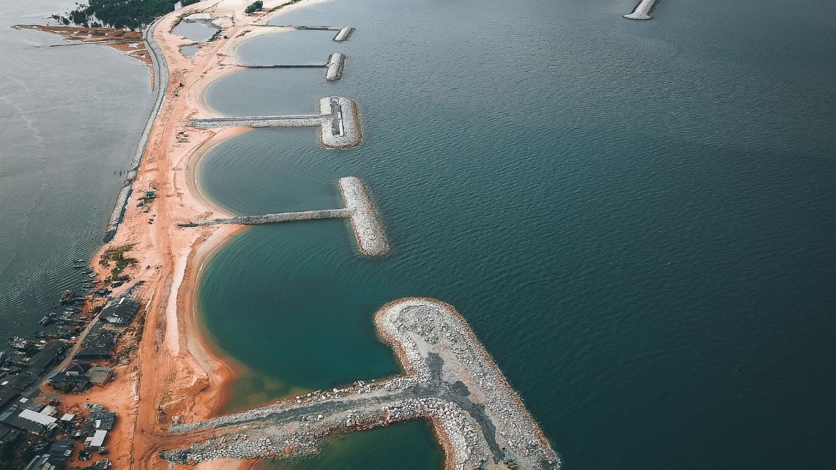 Aerial view of small settlement located on sandy shore near calm sea water
