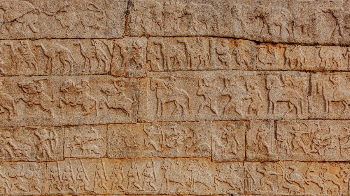 Detailed stone carvings depicting a historical battle scene with warriors and animals.