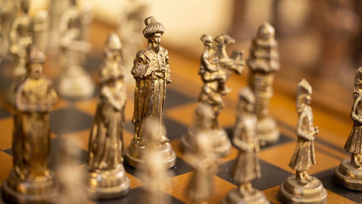Close-up of ornate chess pieces depicting historical figures on a chess board.