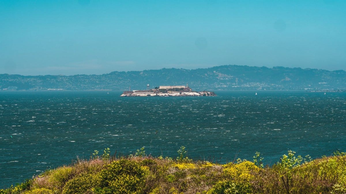 Picturesque view of Alcatraz Island surrounded by San Francisco Bay under clear sky.