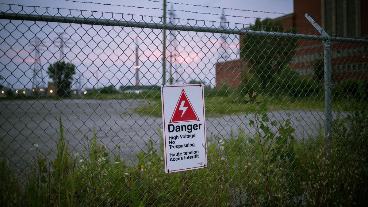 Chain link fence with a danger high voltage sign warns against trespassing.