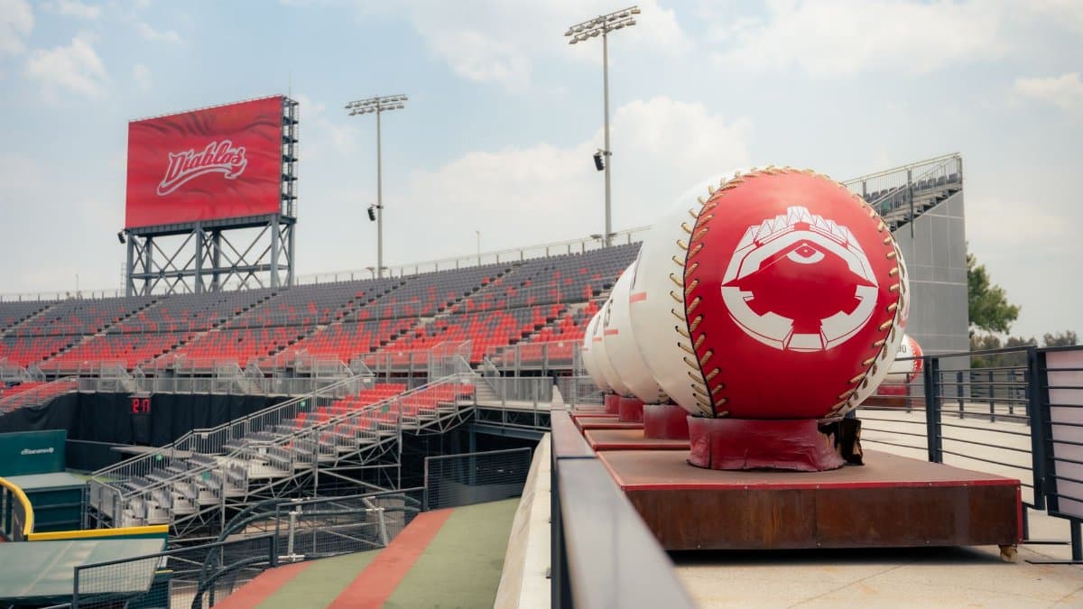 A view of an empty stadium with oversized baseball decorations under a clear sky.
