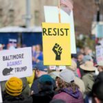Protesters in Baltimore hold signs advocating resistance and social justice. Location: Baltimore, Maryland.