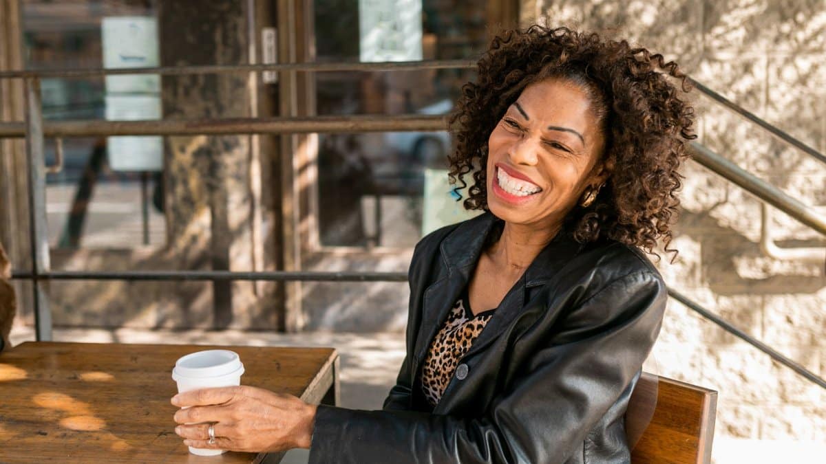 Smiling senior woman relaxing with a coffee at an outdoor cafe, embodying elegant senior style.