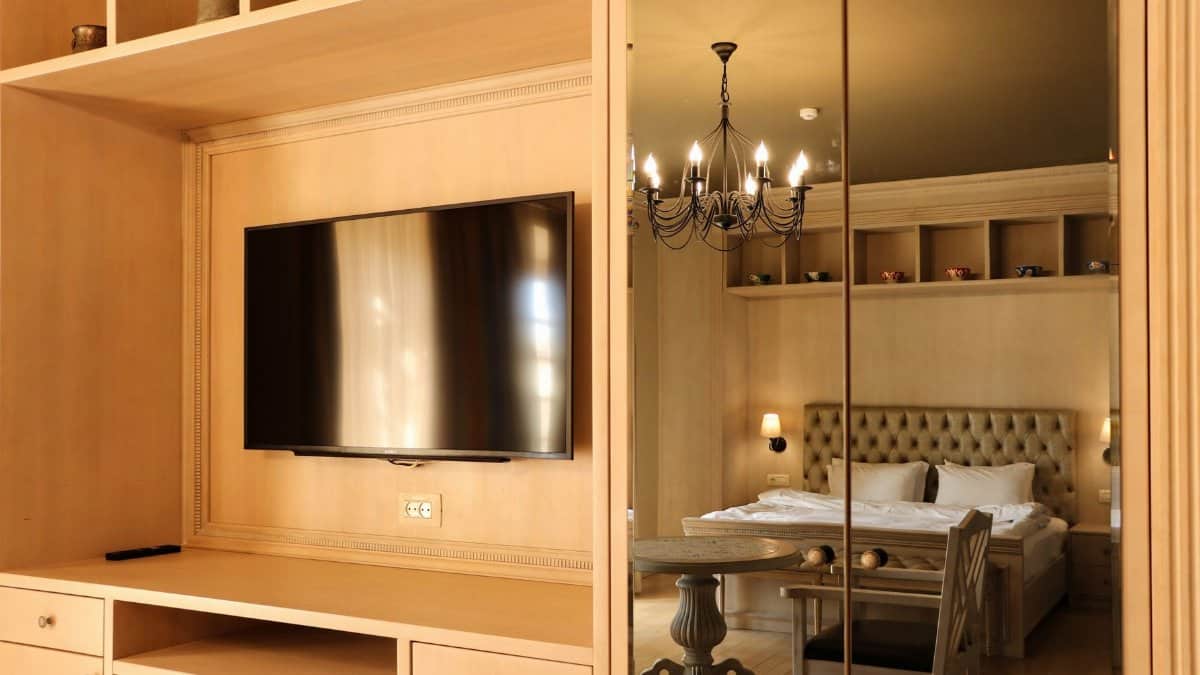 Luxurious hotel room featuring elegant furniture and a large mirror reflecting a chandelier.