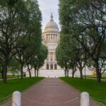 The majestic Rhode Island State House surrounded by lush green trees on a sunny summer day.