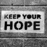 Black and white photo of 'Keep Your Hope' graffiti on a pavement.
