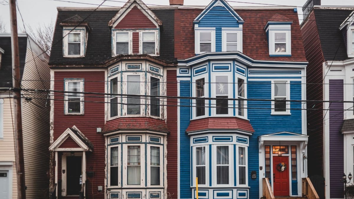 Facade of colorful old fashioned residential house with windows and doors located on street with power lines in town against cloudless sky