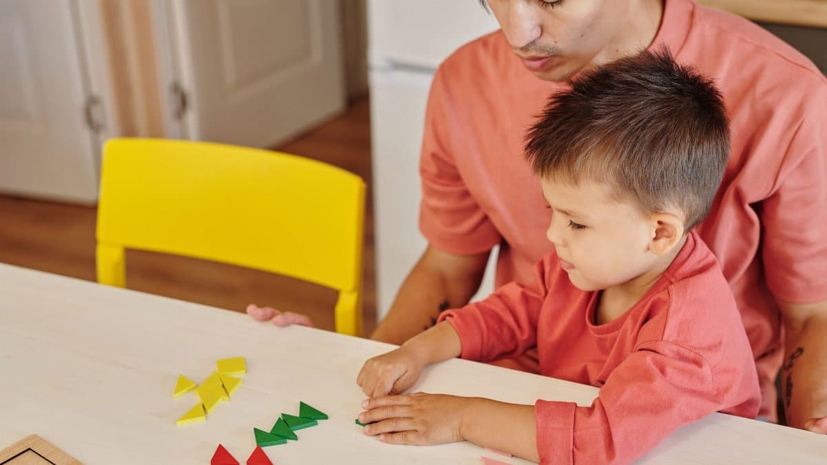 Father and son bonding over educational shapes at home. Bright and colorful scene.
