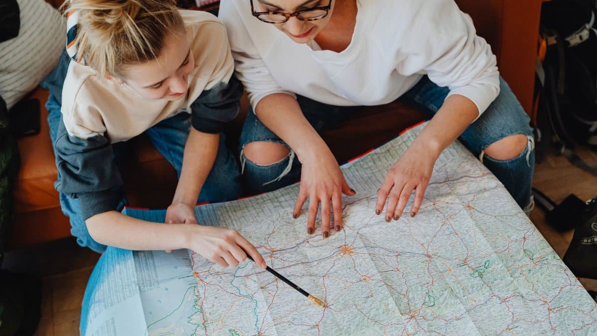 A mother and daughter plan their journey using a map, symbolizing adventure and bonding.