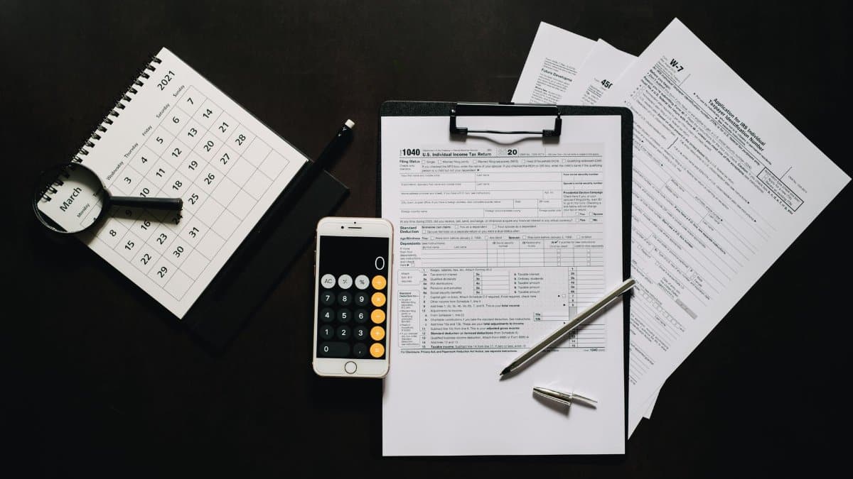 Flat lay of financial tools for tax preparation including forms, calculator, and calendar.