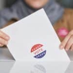 Close-up of hands holding a vote ballot, symbolizing election participation.