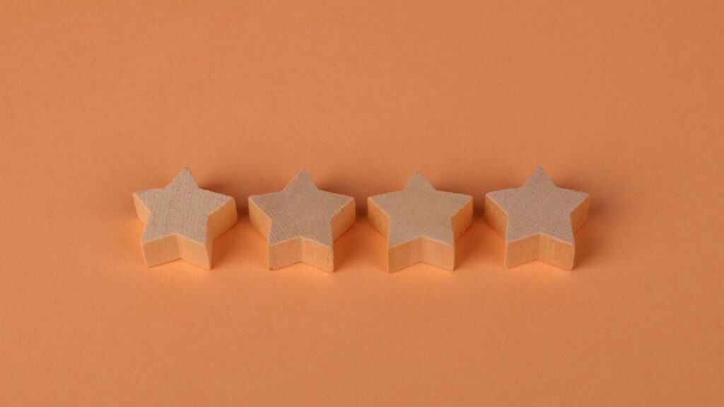 Four wooden star shaped blocks aligned on a plain orange surface, offering minimalist design.