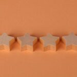 Four wooden star shaped blocks aligned on a plain orange surface, offering minimalist design.